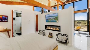Un dormitorio moderno con una cama grande, una chimenea y una vista panorámica a través de amplios ventanales.