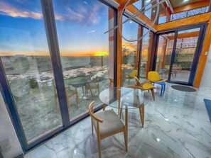 Enjoy a panoramic view of the coastal landscape from this room, featuring a glass table and comfortable seating.