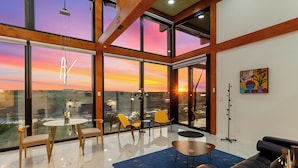 Un interior moderno con ventanas amplias, una mesa de cristal y una alfombra azul.