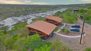 Un edificio moderno con techo rojo, rodeado por un paisaje natural con río y vegetación.