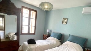 A bedroom with two beds, a wooden floor, a large mirror, and a window with a view. - Village house with garden  (Monségur)