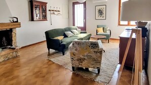 A living room with a fireplace, a sofa, a chair, a rug, and a painting on the wall. - Village house with garden  (Monségur)
