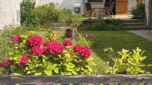 A residential property with a tiled roof, a small outdoor seating area with chairs and a table, and a garden with pink flowers. - Village house with garden  (Monségur)
