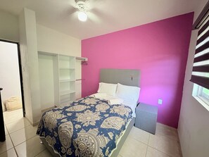 Une chambre à coucher avec un lit, une armoire et une fenêtre avec des stores.