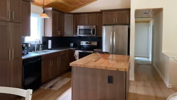 A kitchen with wooden cabinets, a microwave, a refrigerator, and a wooden island. - Howard's Creek Hideaway - Cozy mountain home close to downtown Boone & App State (Boone)