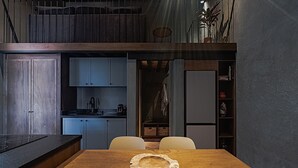 Una cucina moderna con zona pranzo, caratterizzata da un tavolo e sedie in legno, forno a incasso e un'isola con lavello.