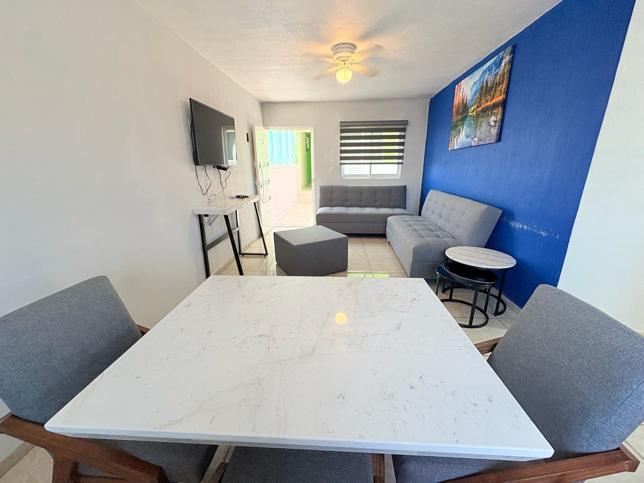 Ein modernes Wohnzimmer mit einem Marmortisch, grauen Sofas und einer blauen Akzentwand.