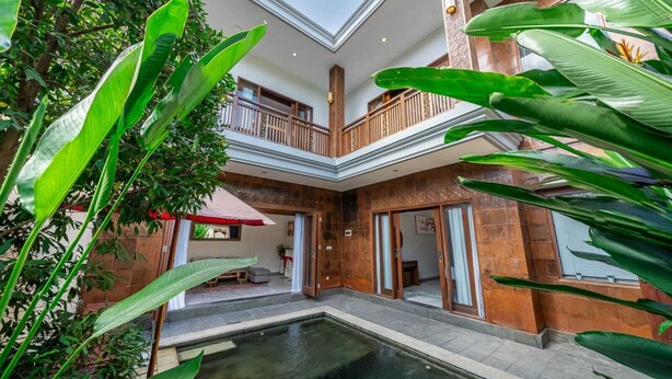 Ein mehrstöckiges Gebäude mit Innenhof, Pool und üppiger Bepflanzung.