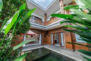 A multi-level building with a central courtyard, a pool, and lush greenery. - Villa Kandel (Jimbaran)
