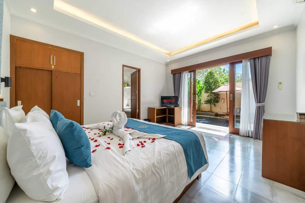 Une chambre d’hôtel équipée d’un lit, d’une télévision, d’un bureau et offrant une vue sur l’extérieur.