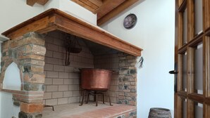 Eine rustikale Außenküche mit Backofen aus Ziegeln, einem Kupfertopf und einem Holzfass.