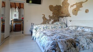 Ein Schlafzimmer mit einem großen Bett, einem an der Wand montierten Fernseher und einer rustikalen Steinwand.
