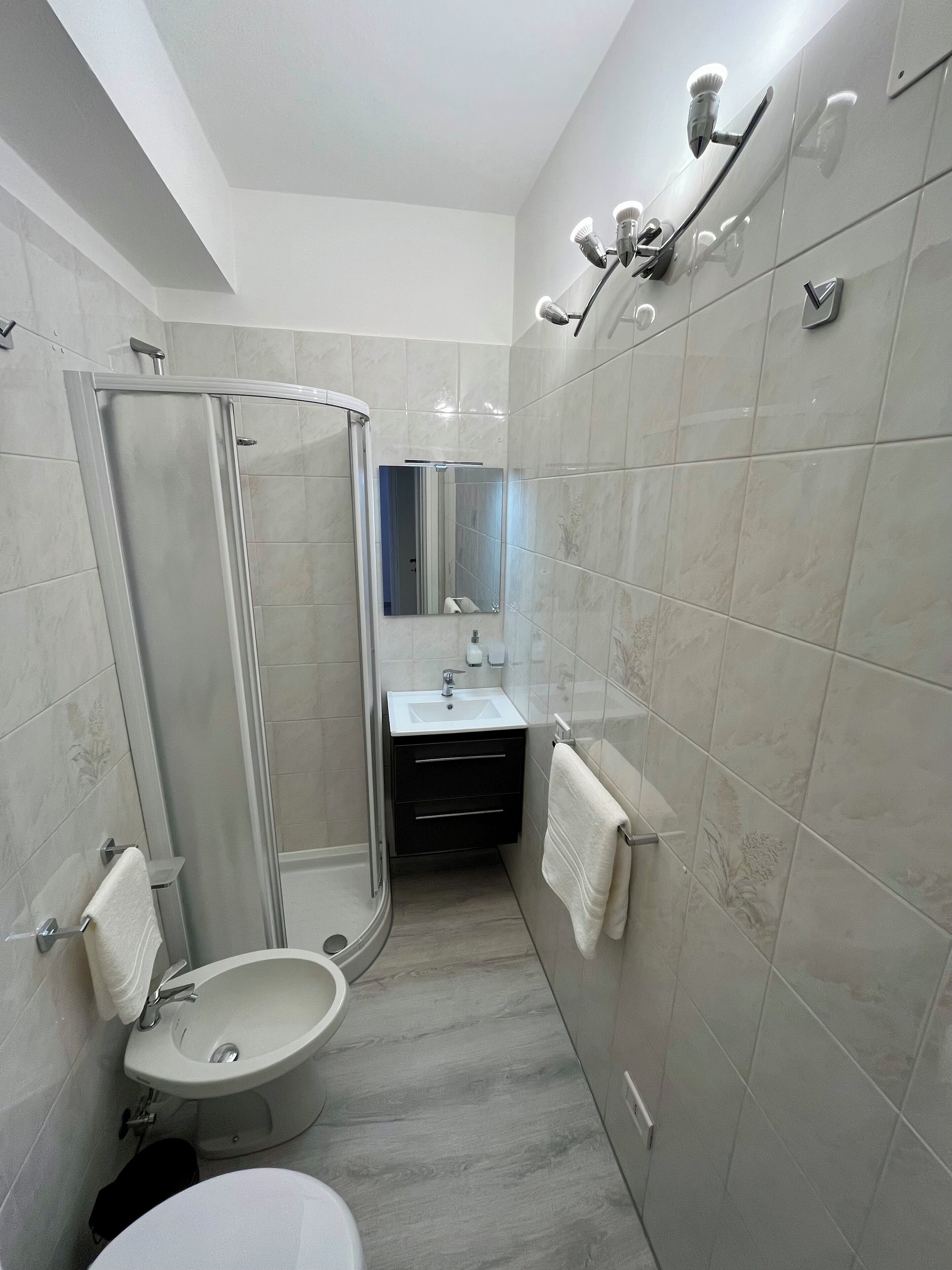 Un baño moderno con cabina de ducha de vidrio, lavabo e inodoro.