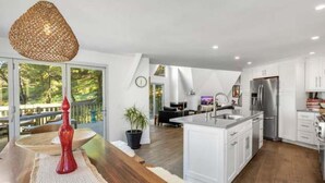 Une cuisine moderne avec des armoires blanches, un réfrigérateur en acier inoxydable et un grand îlot central.