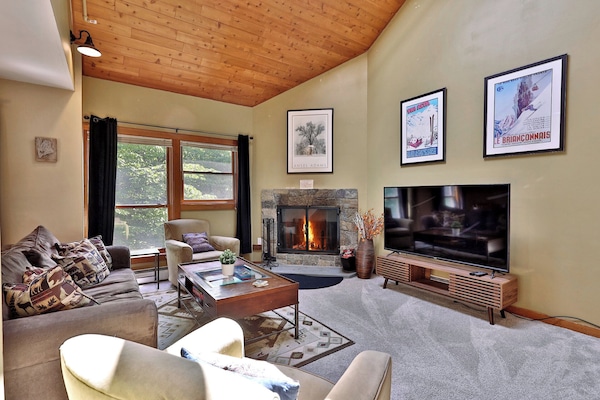 The living room of our charming Trail Creek condo at Killington Resort features a sleeper sofa, a smart TV, a wood-burning fireplace, and a small balcony to enjoy the mountain air.