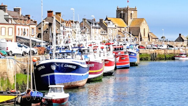 A harbor with multiple boats docked along the waterfront, a historic building with a clock tower, and a row of parked cars along the shore. - 3 bedroom lovely home in La Pernelle (La Pernelle)