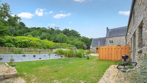 A stone building with a wooden fence, a garden with a pond, and a bicycle. - 3 bedroom lovely home in La Pernelle (La Pernelle)