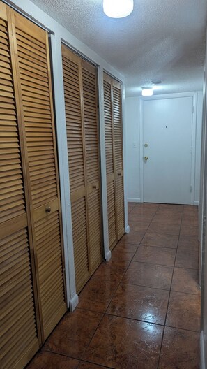 A hallway with wooden sliding doors, a white door, and a tiled floor.
