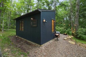 A small cabin with a gravel path leading to it, surrounded by trees. - Evermore Cottage | Hocking Hills, Couples Retreat (Creola)