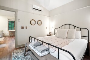 A bedroom with a bed, bedside table, and a bench with towels.