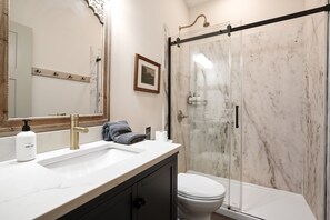 A bathroom with a marble sink, a toilet, and a glass shower enclosure. - Evermore Cottage | Hocking Hills, Couples Retreat (Creola)