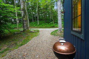 A gravel path leading to a building with a large metal container. - Evermore Cottage | Hocking Hills, Couples Retreat (Creola)