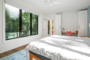 A bedroom with a large window, a bed, a desk, and a wardrobe. - Maren's Hideaway | Hocking Hills, Modern, 40 Acres (Creola)