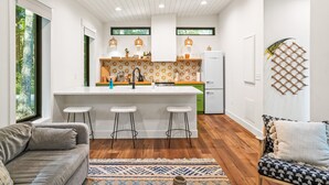 Una cocina moderna con una isla central, taburetes de bar y un refrigerador.
