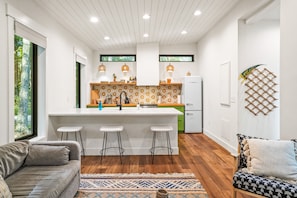 Cocina moderna con una isla central, taburetes de bar e iluminación colgante.