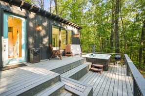 A wooden deck with a hot tub, outdoor seating, and a trash bin.