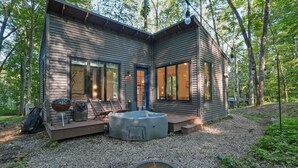 A modern cabin with a fire pit, outdoor seating, and a deck.