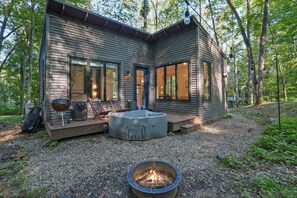 Una cabaña moderna con un brasero, asientos exteriores y una terraza.