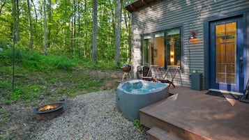 Une terrasse en bois avec un jacuzzi, des sièges d’extérieur et un foyer.
