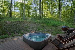 Un jacuzzi en una terraza de madera rodeado por un bosque.