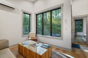 Un salón moderno con un gran ventanal, una mesa de centro de madera y un sofá color beige.