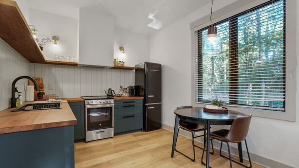 A modern kitchen with wooden cabinets, a built-in oven, a refrigerator, and a dining area with a table and chairs.