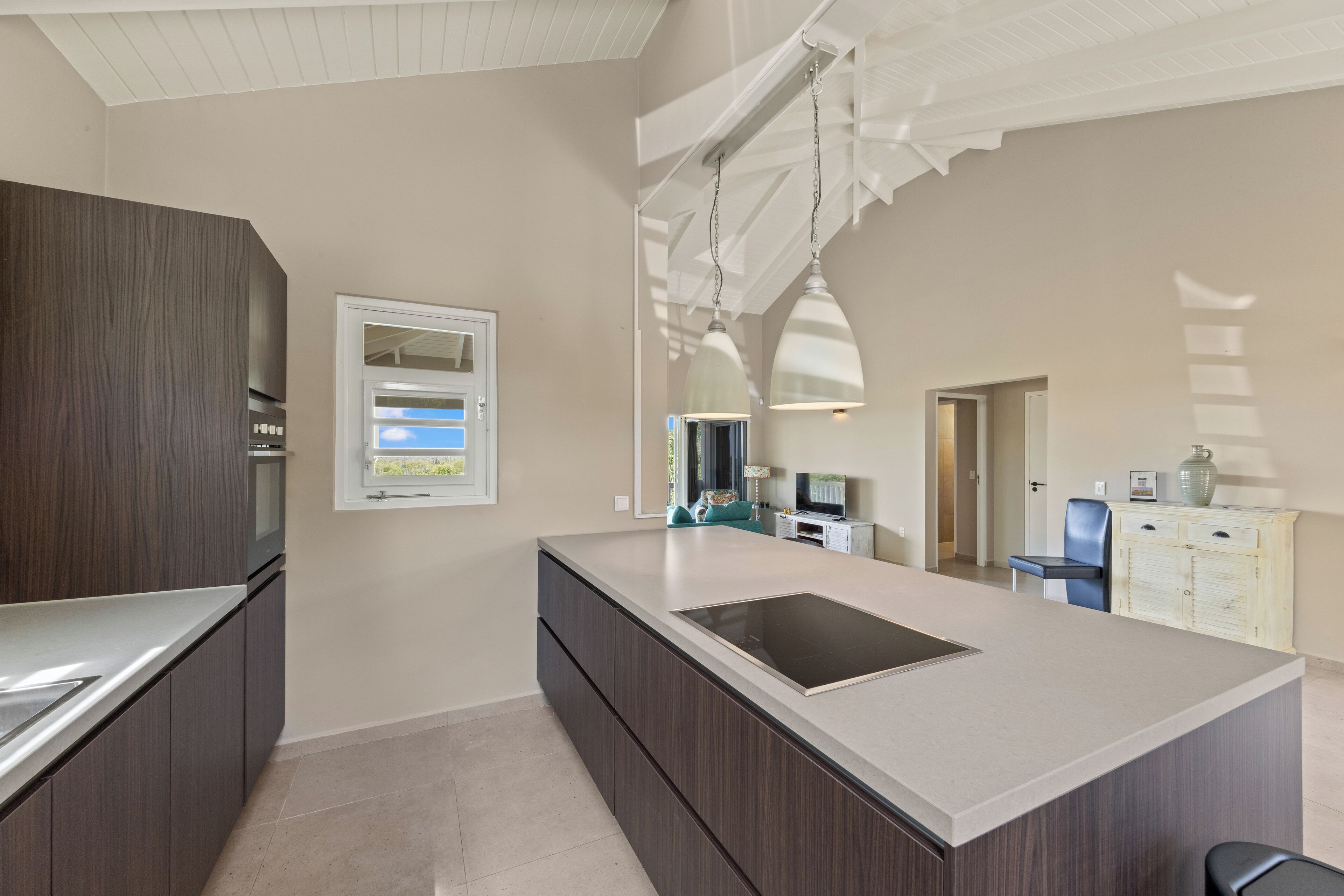 A modern kitchen with a central island, dark cabinetry, and a white ceiling.