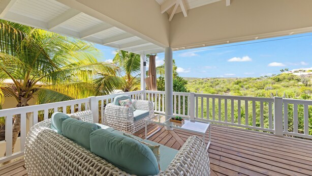 A covered outdoor seating area with wicker furniture and a view of the landscape. - Jan Thiel Jewel (Jan Thiel)