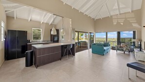 A spacious kitchen with a large island, a dining area with a sofa and chairs, and a balcony with a view. - Jan Thiel Jewel (Jan Thiel)