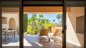 An open patio with a table and two lounge chairs, a clear view of palm trees and a cityscape in the background. - Ref. 421409 (Estepona)