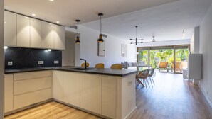 A modern kitchen with a central island, recessed lighting, and a dining area with chairs and a table. - Ref. 421409 (Estepona)