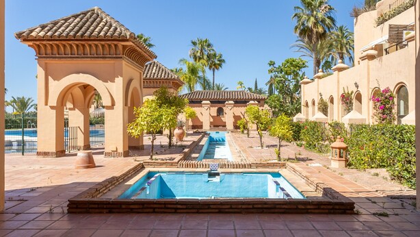 A pool area with a tiled deck, a pergola, and a small fountain. - Ref. 421409 (Estepona)