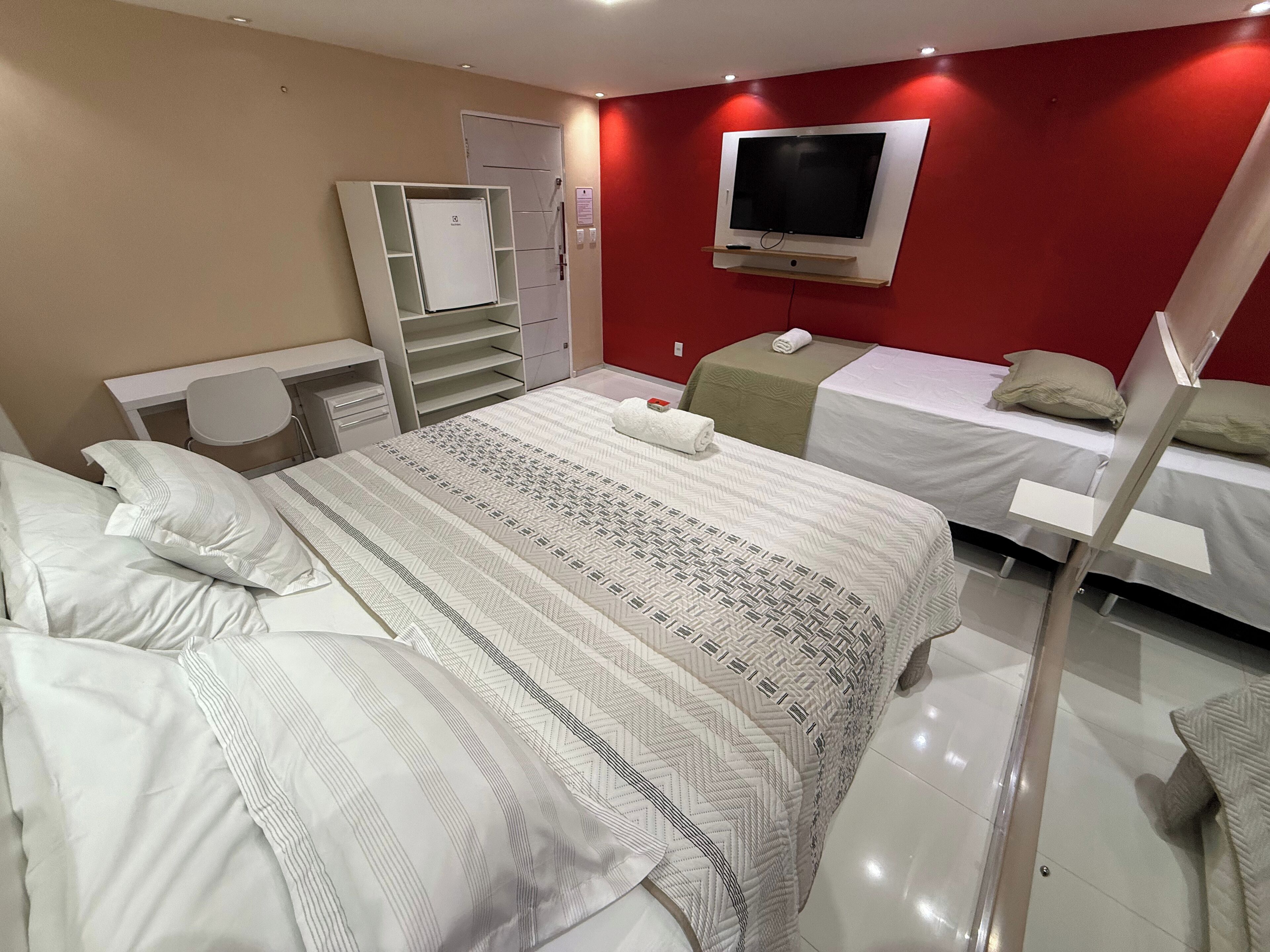 Habitación de hotel con una cama grande, un escritorio, una silla, un televisor y un armario.