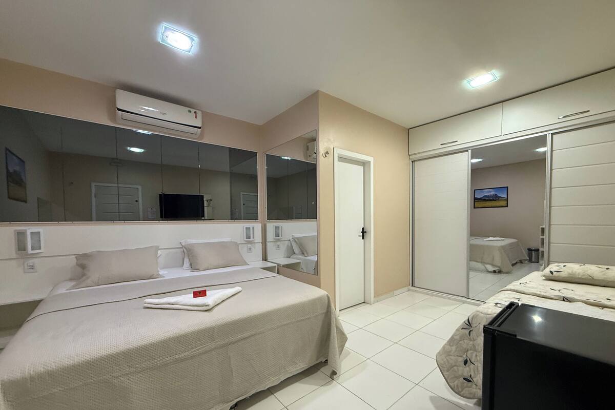A hotel room with a bed, a TV, a wardrobe, and a bathroom.