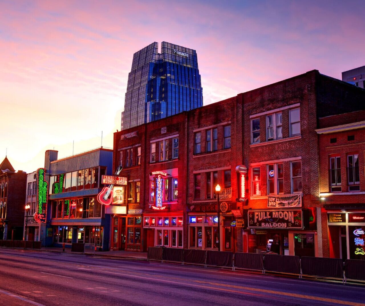 A street lined with brick buildings, including a record shop and a bar.