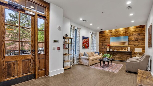 A spacious living room with a wooden floor, a sofa, a coffee table, and a fireplace.