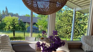 A room with a wooden table, a vase with purple flowers, a candle, and a wicker ceiling fan. - Holiday home close to the beach in Nødebohuse (Hundested)