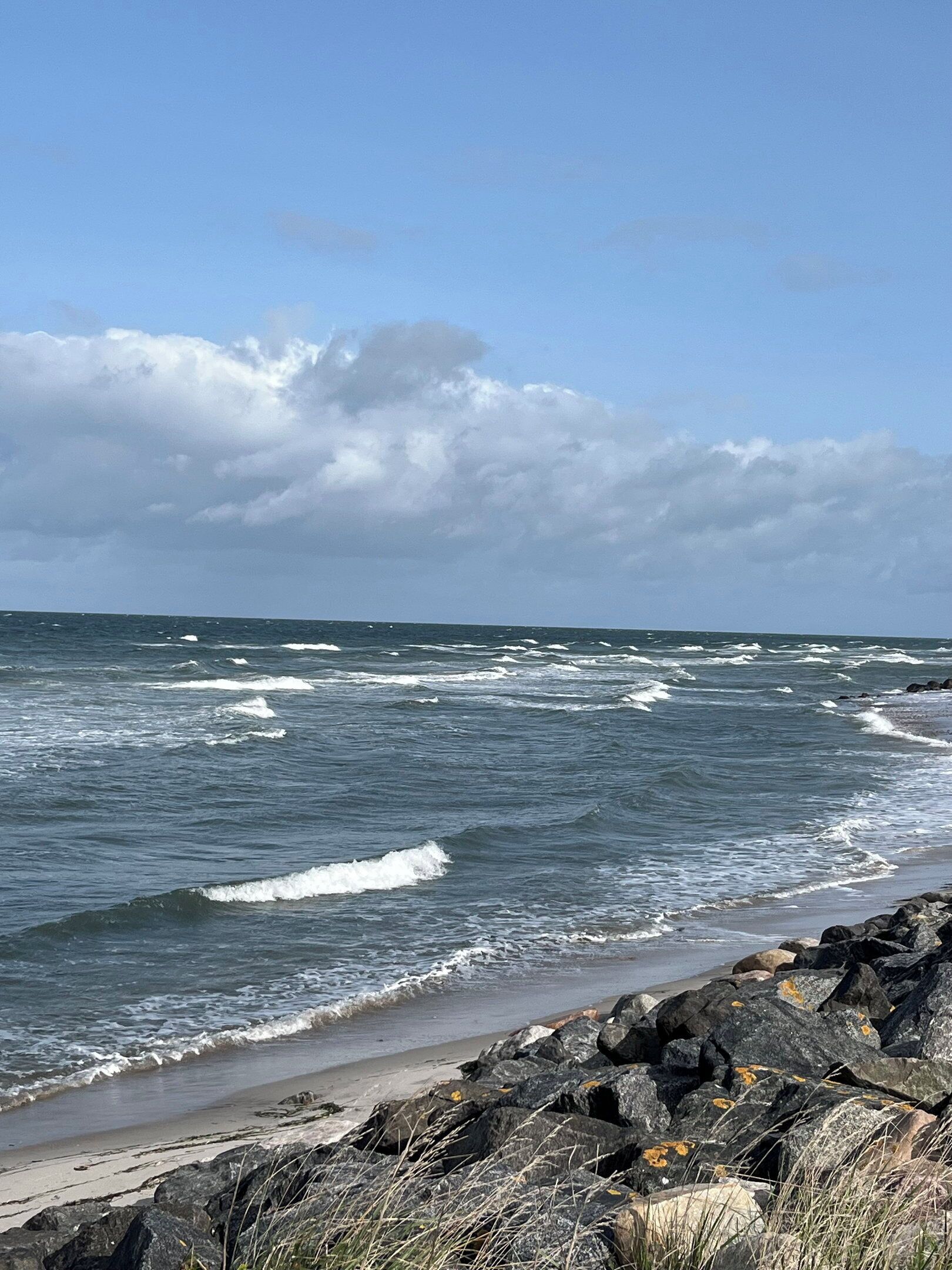 Une côte rocheuse où les vagues s’écrasent sur la plage.