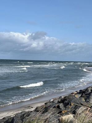 A rocky shoreline with waves crashing onto the beach. - Holiday home close to the beach in Nødebohuse (Hundested)