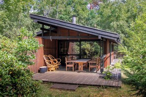 Une terrasse en bois avec des meubles d’extérieur, un espace salon couvert et une cheminée.